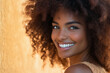 © venusvi - Smiling woman with curly hair against a warm background, exuding joy and confidence.