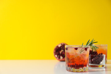 Wall Mural - Red cocktail with fresh pomegranate on a yellow background