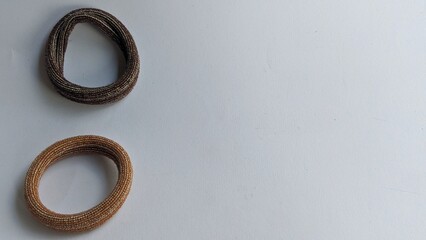 Two hair ties, one brown and one brown and silver, on a white background. Both hair ties have a ribbed texture.