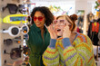 © ReeldealHD images - Female friends trying on sunglasses in a store on vacation