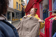 © ReeldealHD images - Young adult woman having fun trying on clothes at a street market