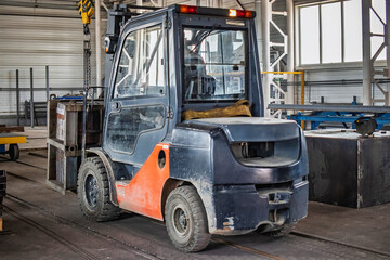 Forklift moving a heavy load through an industrial workshop during daylight hours for efficient material handling