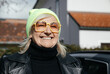 © Ktn - Stylish senior woman in yellow glasses and beanie smiling outdoors in urban setting