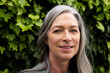 © WavebreakMediaMicro - Smiling mature woman outdoors with green leaves in background, enjoying nature