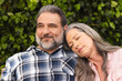 © wavebreak3 - Relaxing outdoors, mature couple smiling as woman rests head on man's shoulder
