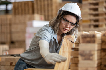 woman wearing safety uniform and hard hat working quality inspection of wooden products at workshop manufacturing wooden. female carpenter worker wood warehouse industry.