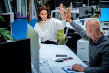 Shot of two coworkers sitting at the office and giving high-five