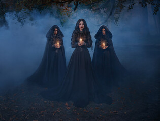 Group of womans walking in night forest tree, holding candles in hands, mystical cult three girls priestesses. Black clothes dress cape hood on head. Beautiful gothic queen with maids. Dark long hair.