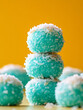 © SashaMagic - Stack of blue coconut candy balls on yellow background.