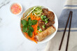 © Austockphoto - Beef noodle salad topped with fried lumpia with salad dressing next to it.