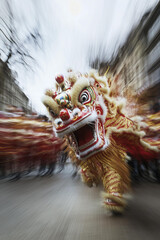 Chinese lion or dragon dance in the street, with golden and a red body, wearing white and colorful patterns on its head. The photo uses a motion blur 