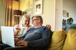© Marko Geber - Senior couple online shopping on laptop on the couch at home