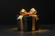 © Olha Ye - Black Friday. Elegant black gift box with gold ribbon on dark background