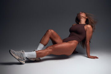 View of determined young sportswoman jumping and posing in the air, on white studio background. Serious fitness woman, posing. muscles fitness