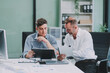 © ARMMY PICCA - Two businessmen working together Analyze financial reports with charts and graphs while using the calculator to calculate budget, income, taxes, business growth. Startup business idea.