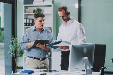 Two businessmen working together Analyze financial reports with charts and graphs while using the calculator to calculate budget, income, taxes, business growth. Startup business idea.