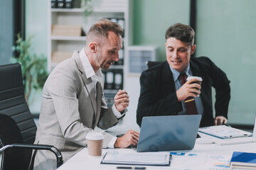 two businessmen working together analyze financial reports with charts and graphs while using the ca