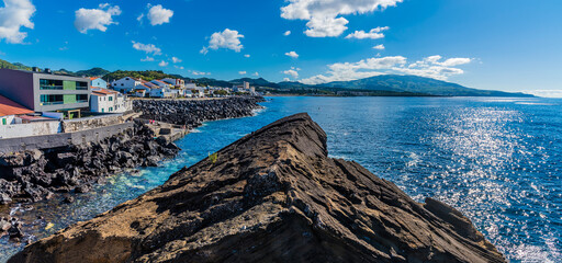 Wall Mural - A view over a rocky outcrop beside the Dog Face Islet down the coastline of the island of San Miguel in the Azores in summertime