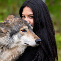 Wall Mural - Young woman with long black hair hugging wolf,