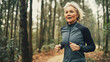© Taras Vykhopen - Energetic senior woman jogging on a forest path during an active morning