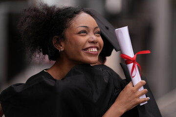 Two graduates in caps and gowns beam with joy, embracing and cheering in celebration. Their wide smiles and enthusiastic expressions capture a proud and happy moment of academic achievement.