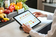 © Viktoriia - Digital meal planning and nutrition tracking on tablet in modern kitchen