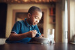 © peopleimages.com - African kid, boy or eating food in home for nutrition, hungry or healthy development at table. Happy child, pasta or spaghetti meal in house for lunch, dinner or cuisine with water at kitchen counter