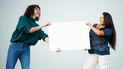 Two women holding blank white sign together