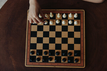 Strategy in action A person deeply focused on playing a game of chess on a classic black and white checkerboard board