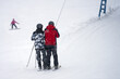 © ROMAN DZIUBALO - Pair climbing on T - bar on a ski slope. A man and a child on skis are towed upwards.
