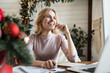 © InsideCreativeHouse - Happy freelance business woman working with documents getting good news from paper letter sitting at table with laptop in home office with Christmas decoration tree looking away smiling laughing