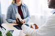 © Maria Vitkovska - African American doctor holding bottle of pills while consulting female patient in clinic