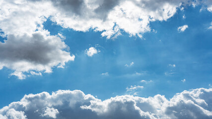 Wall Mural - background of backlit cumulus white clouds bodies floating in clear blue sky