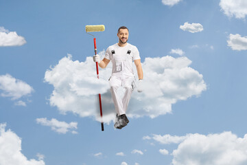 Wall Mural - Painter holding a paint roller and sitting on a cloud