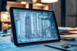 © NOORULHASSAN - Tablet displaying skyscraper models and blueprints in a contemporary architecture workspace