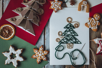 Wall Mural - Cute handmade postcard with fir tree embroidering with green threads on wooden background. Homemade gingerbread cookies. Holiday craft, family tradition, quality time, simple easy do it yourself decor