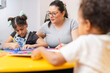© Carlostock - A Colombian Latina preschool teacher teaching and supporting her students with classroom projects