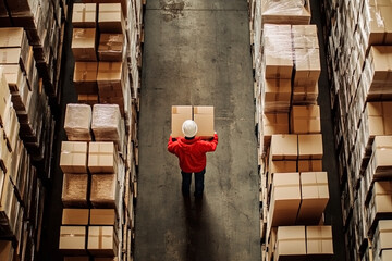 Aerial view of a logistics employee handling inventory boxes surrounded by organized rows of packed good