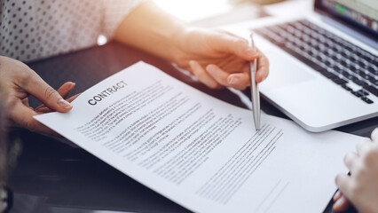 Business people sitting and discussing contract in office, closeup. Partners or lawyers working together at meeting before signing papers. Teamwork and partnership