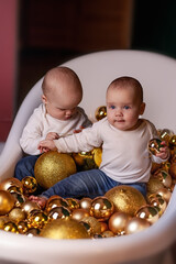 Two dels are sitting in a bathroom filled with golden balls. The concept of Christmas