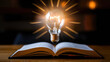 © Hound - A light bulb is shining through the pages of a book. The light bulb represents knowledge and the book represents learning
