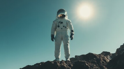 Wall Mural - An astronaut stands on rocky terrain under bright sunlight, with a clear blue sky in the background