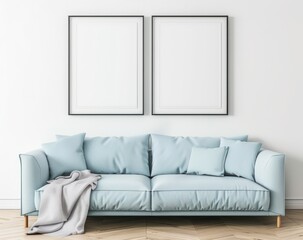 A light blue sofa with two pillows and a blanket sits in front of a white wall with two black framed blank posters The floor is a light wood with a herringbone pattern