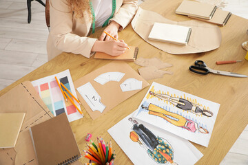 Wall Mural - Female fashion designer drawing at table in studio, closeup