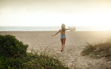 Ocean, woman and running with fun on break for summer holiday, adventure and relax. Back view, female person and open arms at beach with excitement for vacation for chilling, rest and fresh air