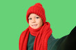 © Pixel-Shot - Cute little Asian boy in warm clothes taking selfie on green background