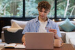 © Wavebreak Media - Christmas time, At home, young man using laptop and credit card for online shopping