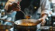 © Chatchanan - A Thai chef balancing flavors in a hot and sour Tom Yum soup, tasting for the perfect