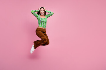 Photo of lovely cheerful woman hand touch head jump up wear green stylish clothes isolated on pink color background