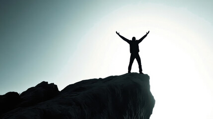 Silhouette of a man on mountain top with arms raised in triumph